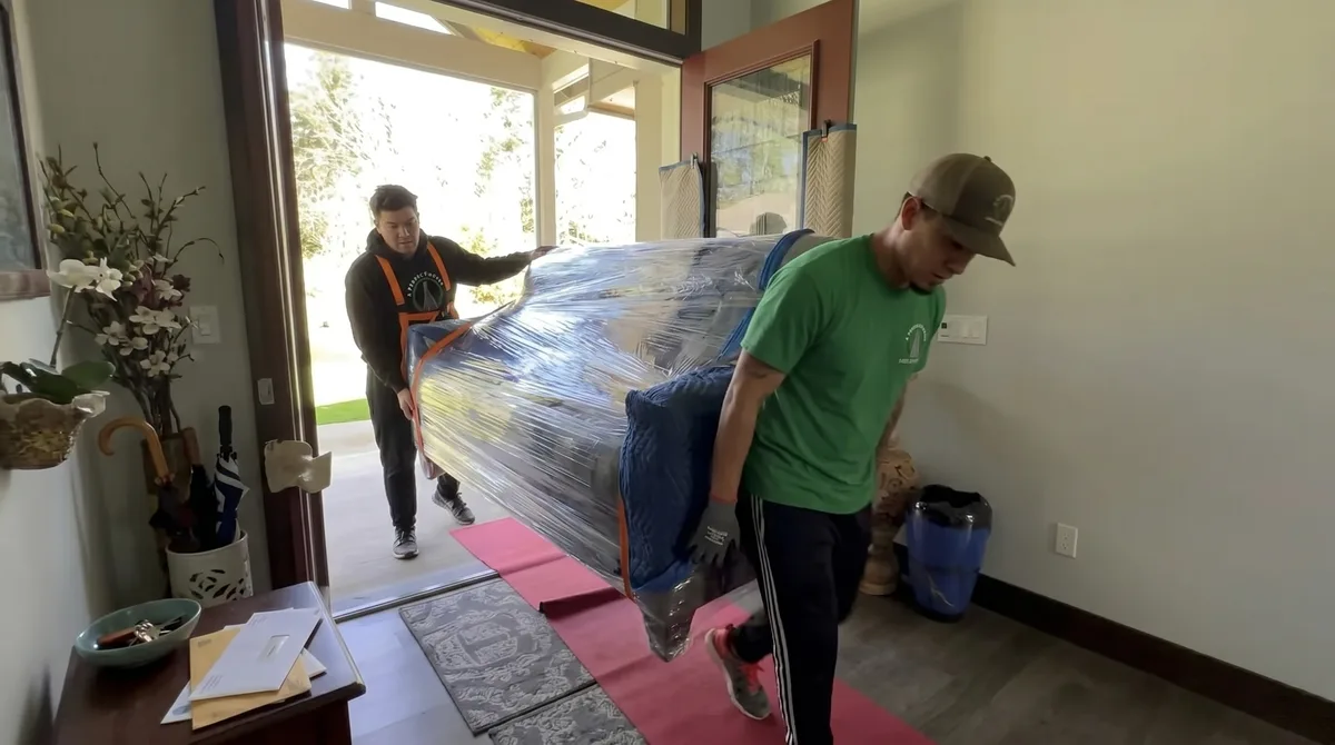 A Perfect Mover crew carrying wrapped furniture through a home entryway